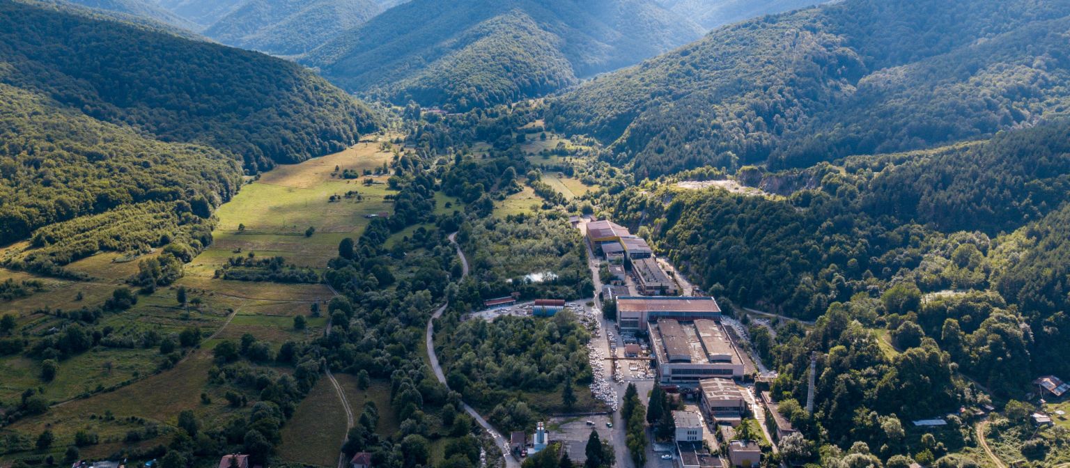 Gestão de recebíveis: A imagem mostra uma vista aérea da fábrica de mármore em Berkovitsa, rodeada por muitas árvores num vale. Devido ao empenho da EOS, a empresa tradicional foi preservada.