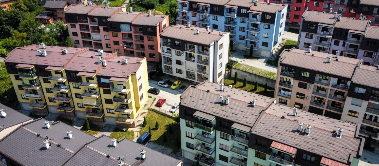NPL garantidos por imóveis: vista aérea de um complexo residencial vibrante com edifícios coloridos rodeados de áreas verdes na Bósnia e Herzegovina