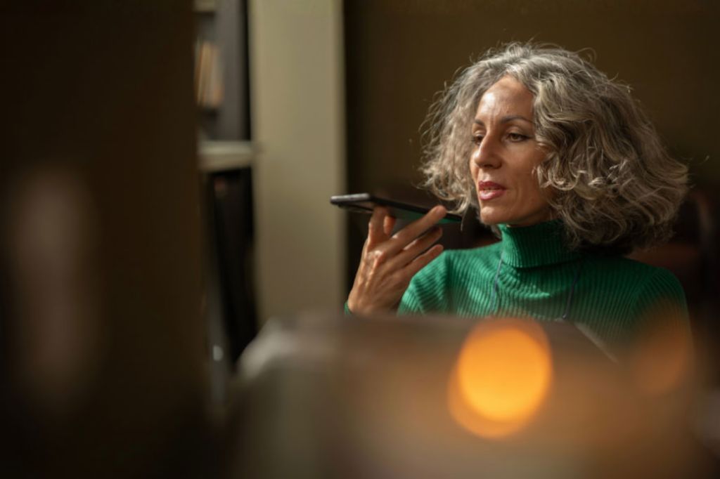 Uma mulher com um telemóvel na mão está a falar com inteligência artificial.