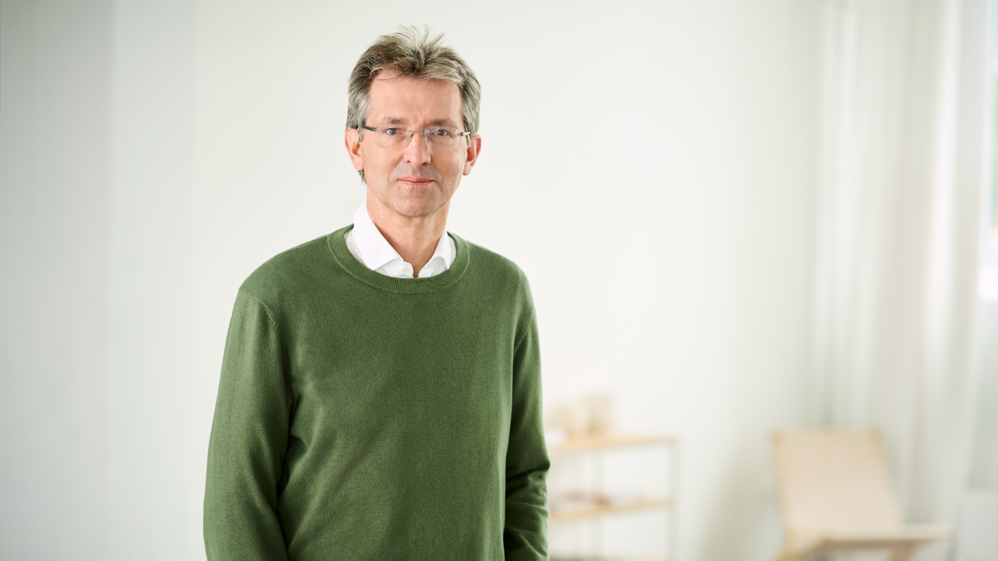 Justus Hecking-Veltman, CFO, está numa sala iluminada e veste um pulôver verde com uma camisa branca.