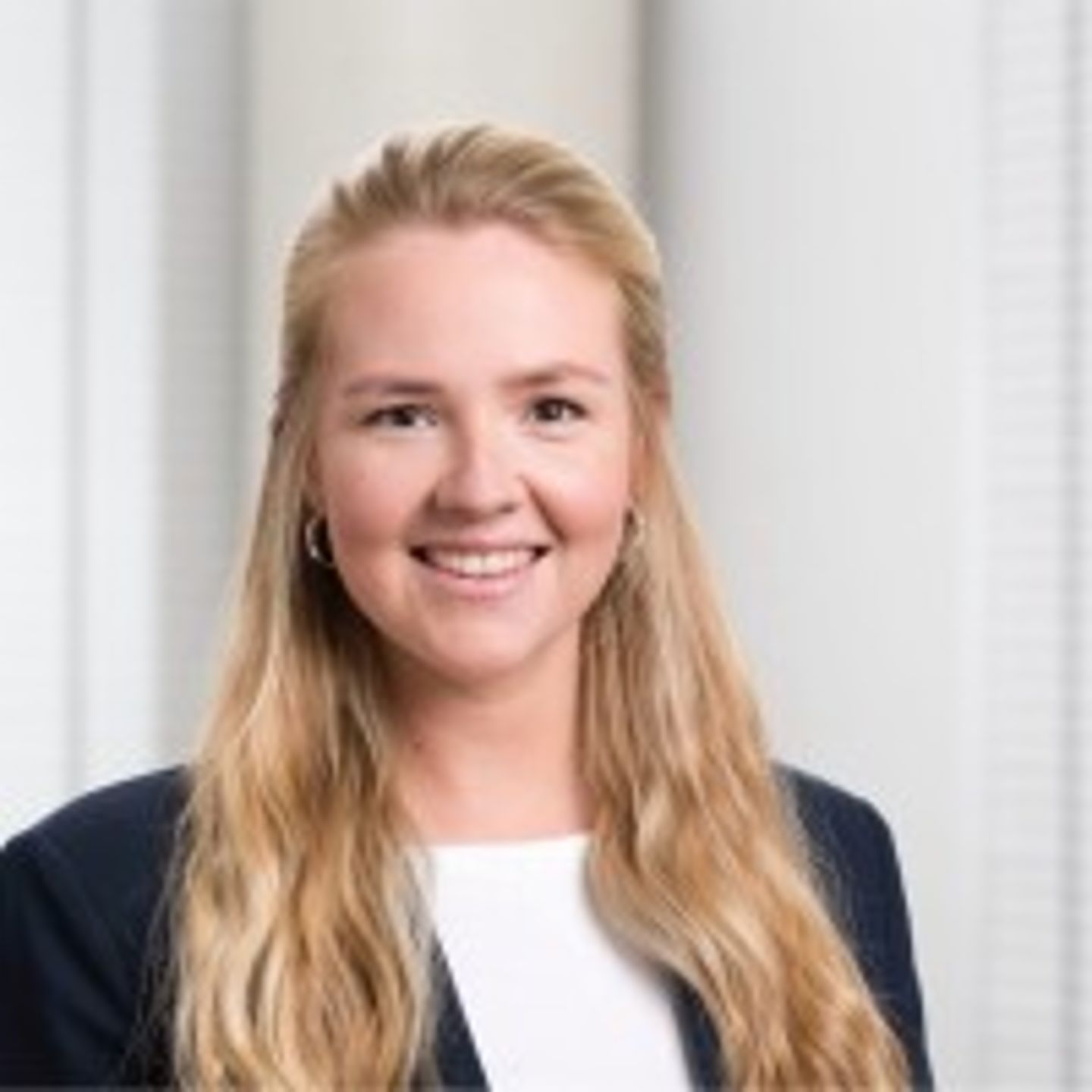 Portrait photo of Jule Terörde, smiling, long blonde hair, dark blue business attire, Consultant ESG Strategy & Corporate Development at EOS