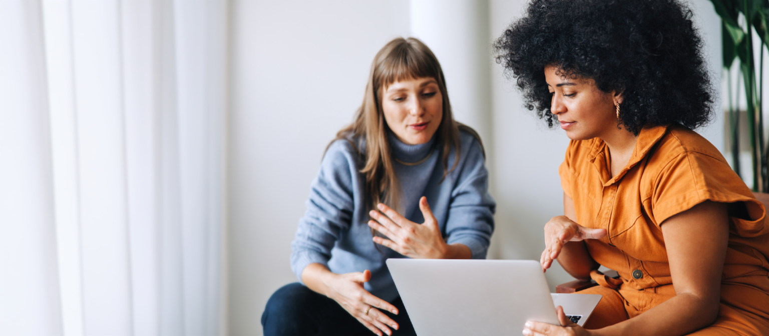 Jovem mulher no celular ao lado de um membro da equipe EOS com fones de ouvido e duas mulheres conversando
