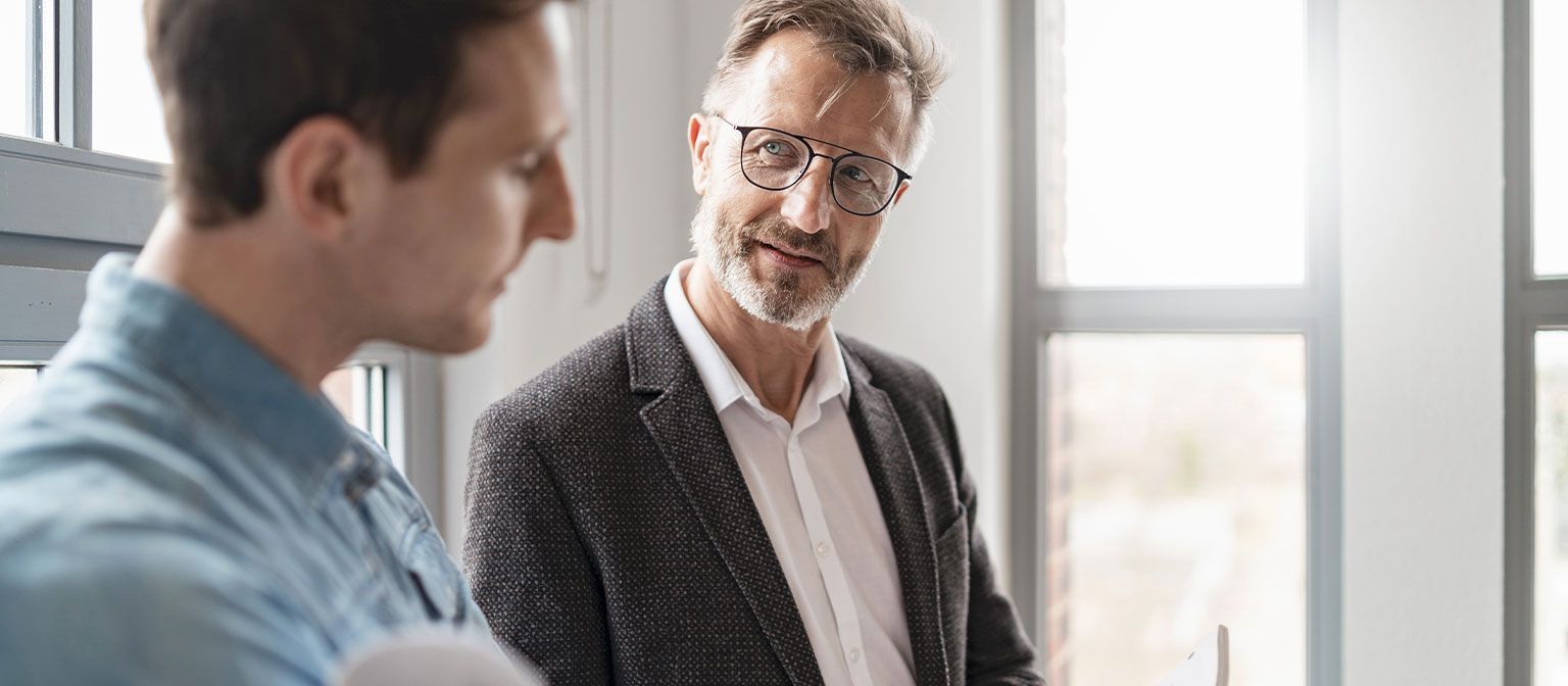 Dois homens num escritório estão a discutir os resultados do estudo "European Payment Practices 2025" do Grupo EOS sobre a digitalização na gestão de recebíveis.