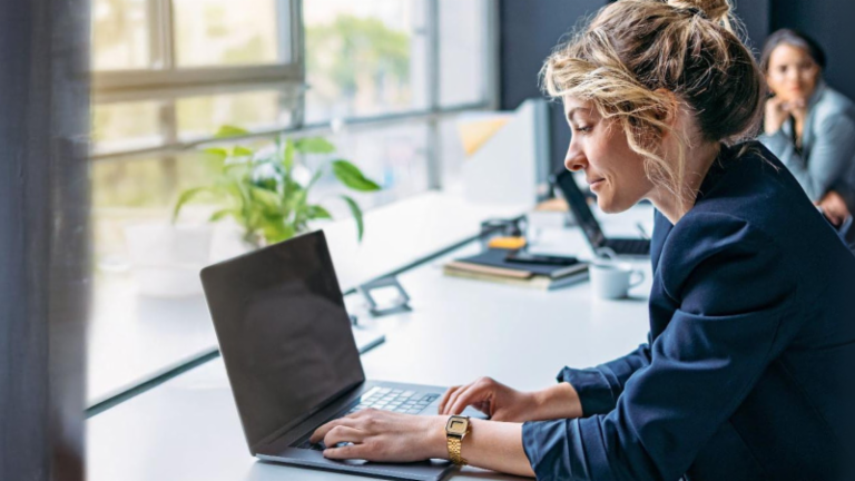 Jovem mulher a trabalhar num portátil num escritório moderno.
