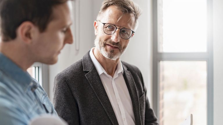 Dois homens num escritório estão a discutir os resultados do estudo "European Payment Practices 2025" do Grupo EOS sobre a digitalização na gestão de recebíveis.