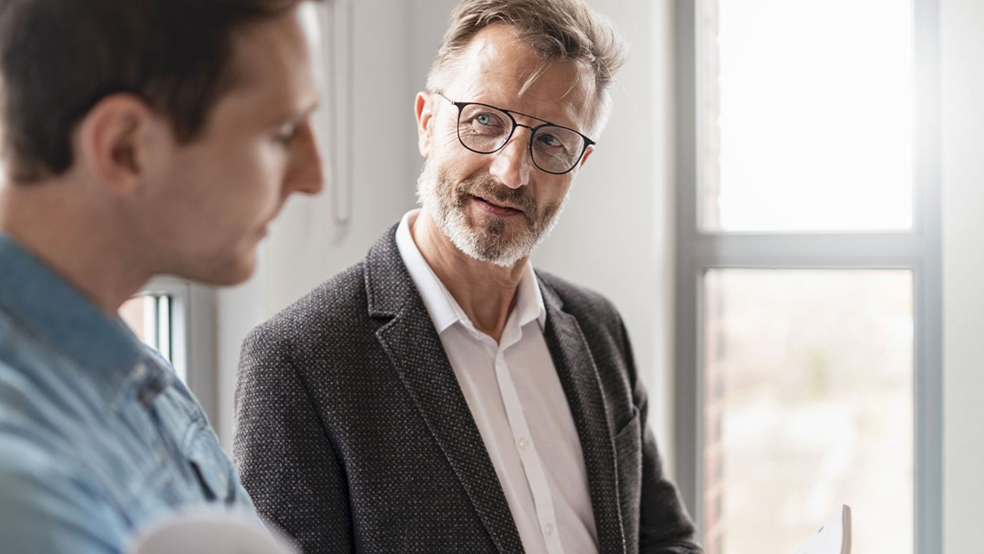 Dois homens num escritório estão a discutir os resultados do estudo "European Payment Practices 2025" do Grupo EOS sobre a digitalização na gestão de recebíveis.