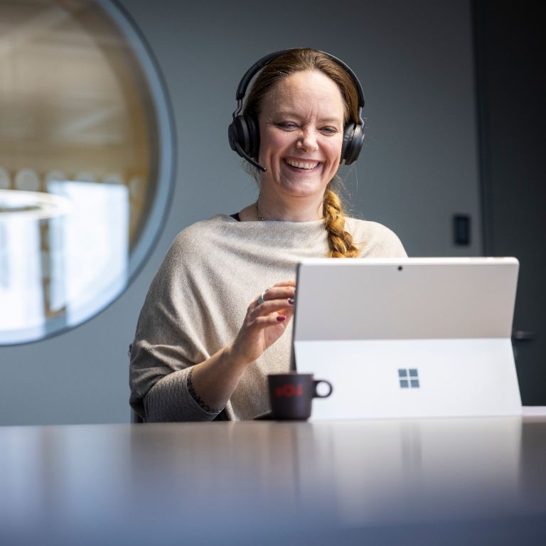 Um colaborador da EOS usa um headset e é visto sorrindo enquanto conversa com um interlocutor digital.