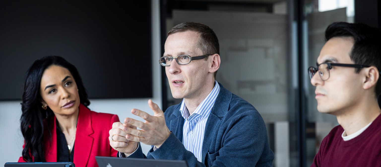 Três pessoas conversam em um escritório.