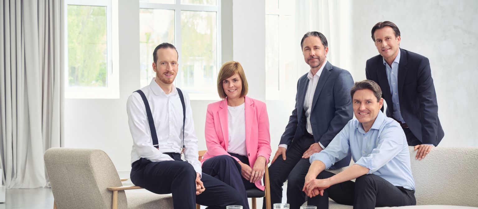 Conselho de Administração do Grupo EOS (da esquerda para a direita: Sebastian Pollmer, Dra. Eva Griewel, Marwin Ramcke, Dr. Stephan Ohlmeyer, Carsten Tidow), em uma sala iluminada olhando diretamente para a câmera