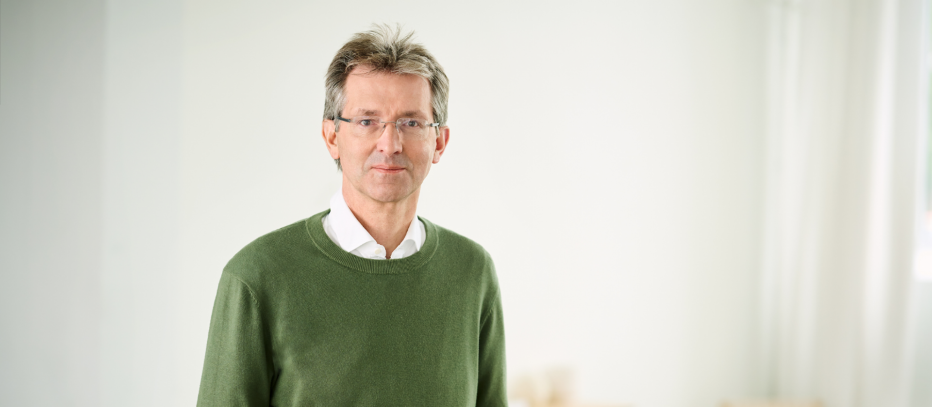 Justus Hecking-Veltman, CFO, está numa sala iluminada e veste um pulôver verde com uma camisa branca.