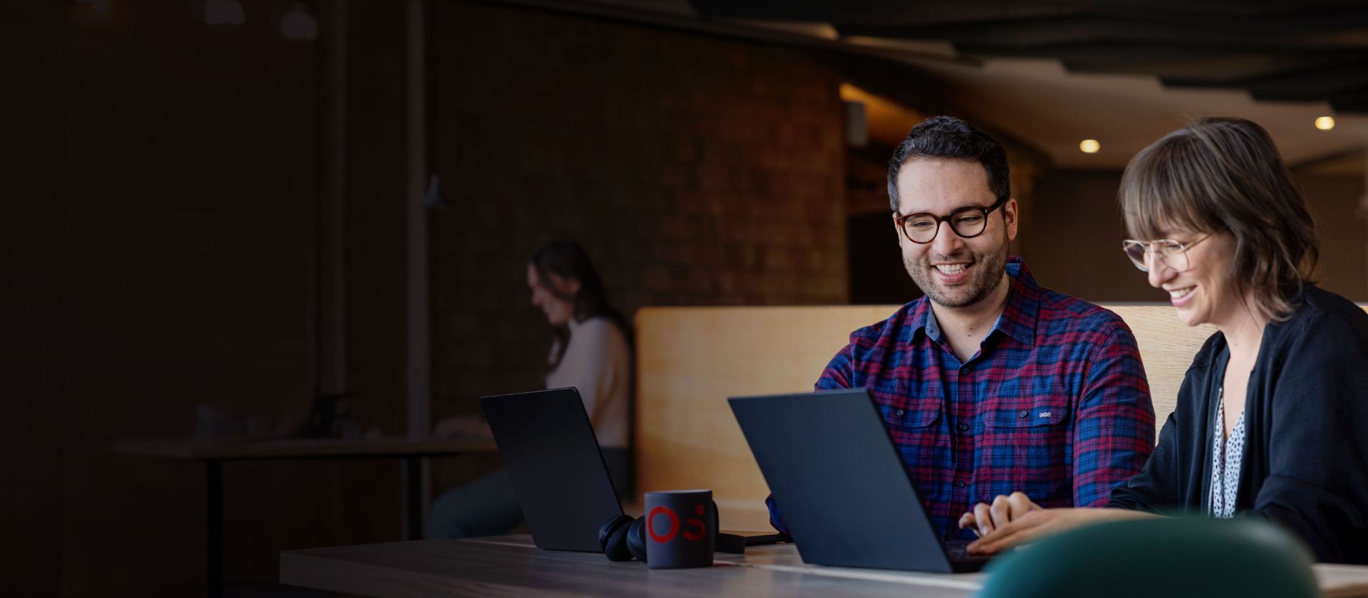 Dois colaboradores da EOS olham para um laptop juntos enquanto estão absortos em uma conversa.