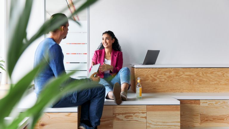 A man and a woman having a relaxed-looking conversation, as a symbolic image of a corporate culture where employees have autonomy.