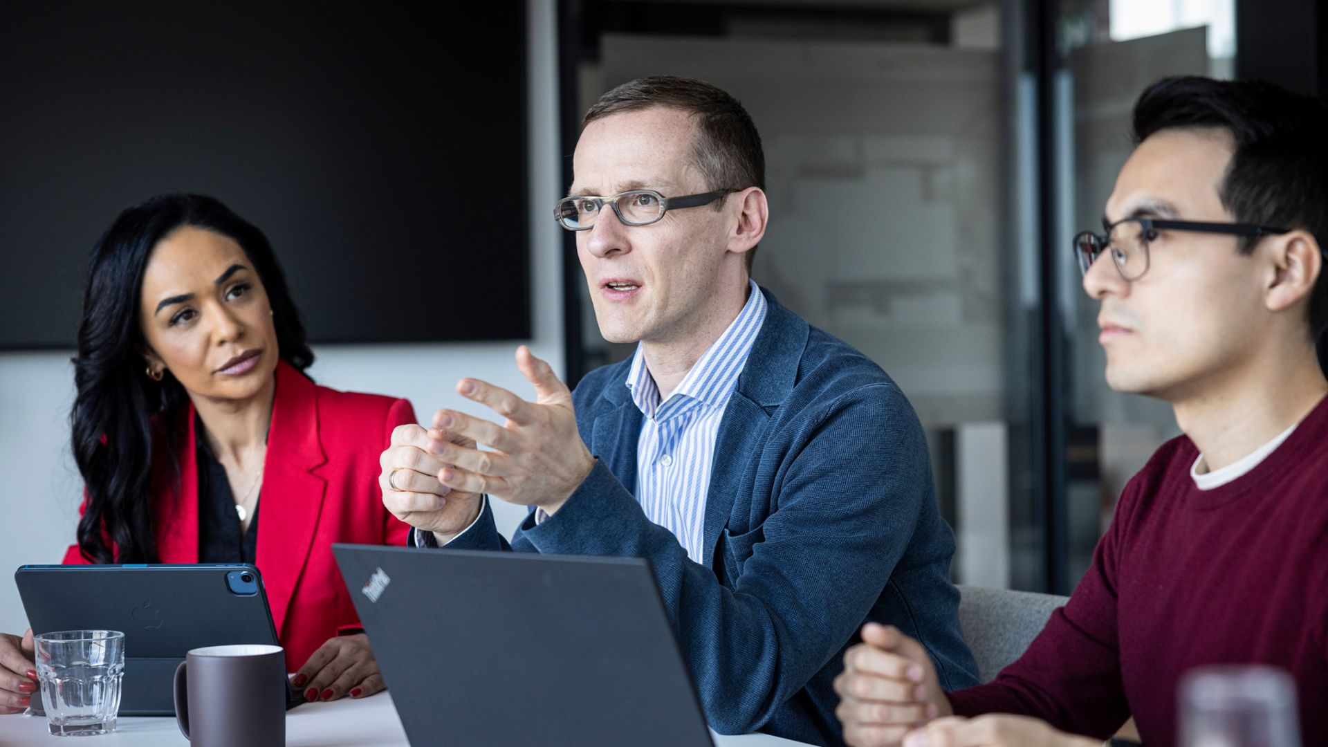 Três pessoas conversam em um escritório.