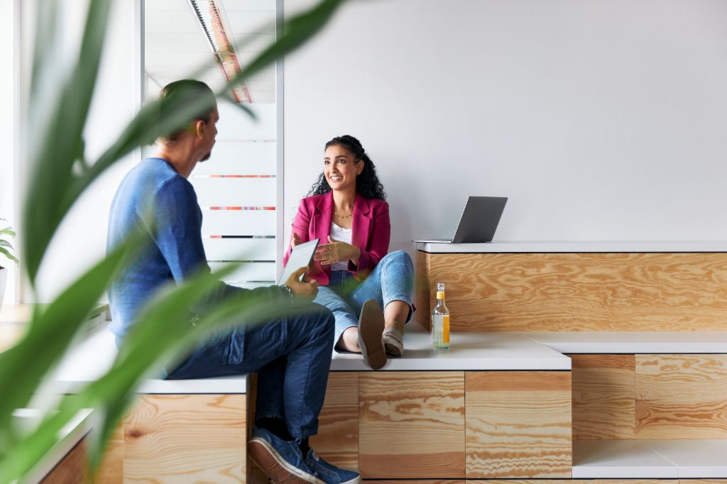 A man and a woman having a relaxed-looking conversation, as a symbolic image of a corporate culture where employees have autonomy.