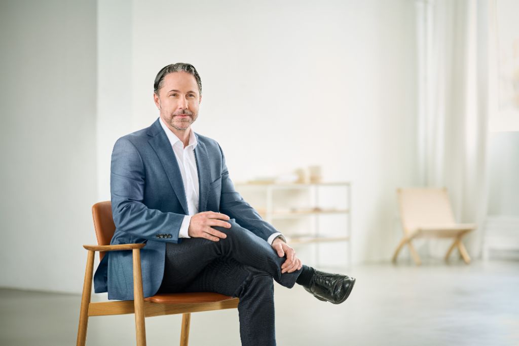 Retrato de Marwin Ramcke, Presidente do Conselho de Administração do Grupo EOS, em uma sala iluminada vestindo um blazer escuro