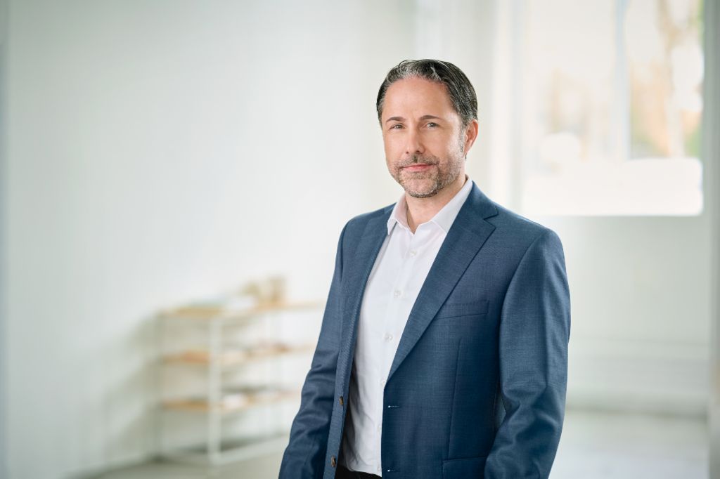 Retrato de Marwin Ramcke, Presidente do Conselho de Administração do Grupo EOS, em uma sala iluminada vestindo um blazer escuro
